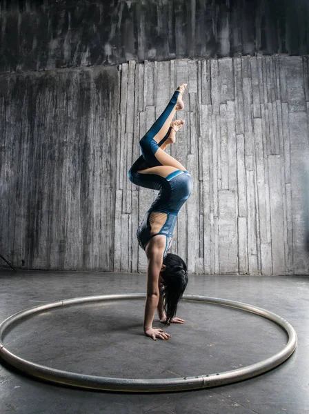 Young female Acrobat Standing on Hand over gray background in photo studio. Flexible Woman Circus Gymnast, Gymnastics Handstand.