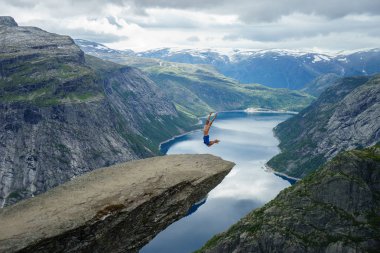 Genç adam atlamak kenarında Trolltunga. Norveç