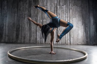 Genç kadın Acrobat ayakta yandan fotoğraf Studio gri arka plan üzerinde. Esnek kadın sirk jimnastik, jimnastik amut.