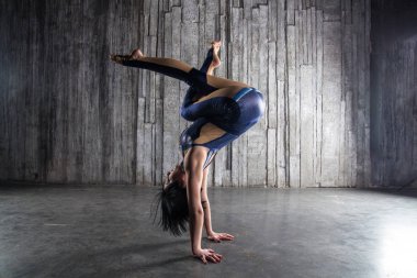 Genç kadın Acrobat ayakta yandan fotoğraf Studio gri arka plan üzerinde. Esnek kadın sirk jimnastik, jimnastik amut.