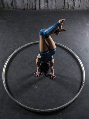 Genç kadın acrobat yandan büyük metal çember içinde ayakta. Jimnastik amut.