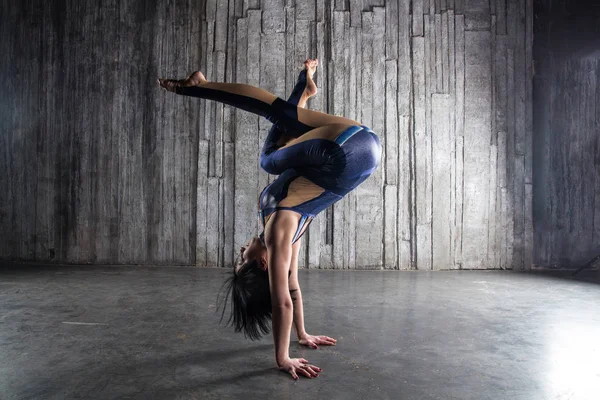 Genç kadın Acrobat ayakta yandan fotoğraf Studio gri arka plan üzerinde. Esnek kadın sirk jimnastik, jimnastik amut.