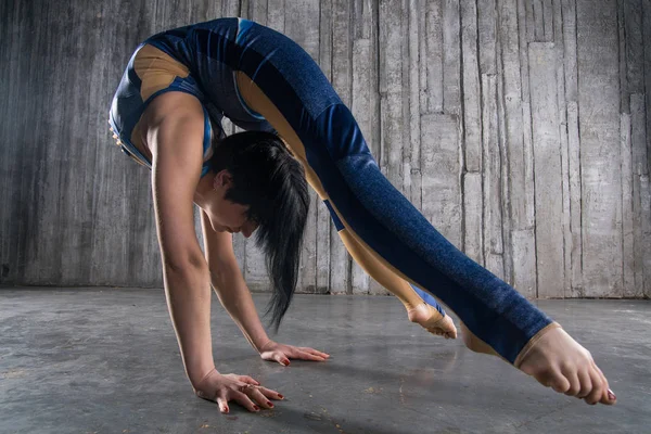 Young female Acrobat Standing on Hand over gray background in photo studio. Flexible Woman Circus Gymnast, Gymnastics Handstand.