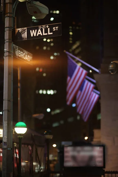 Broadway and Wall Street Signs at the night with US flags on background, Manhattan, New York