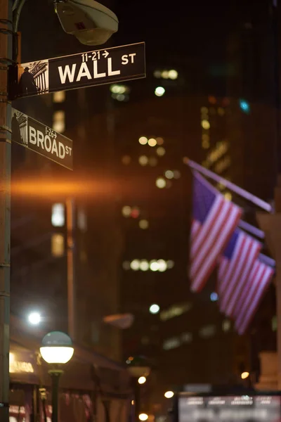 Broadway and Wall Street Signs at the night with US flags on background, Manhattan, New York