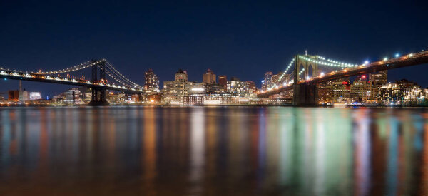 Brooklyn and Manhattan Bridge with Skyline at night and nice blurred reflection in the river at night