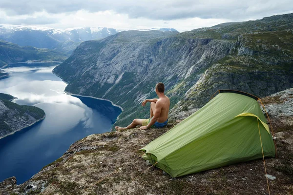 Norwegian fjord landscape with camping tent and young traveller. concept of travel and freedom