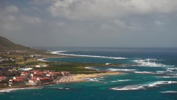 Kilátás St. Kitts sziget felett lakott területen, és beaces az előtérben és a buja zöld hegyek — Stock videók