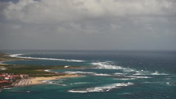 Una vista sobre la isla de St. Kitts con zona residencial y playas en primer plano y exuberantes colinas verdes — Vídeo de stock