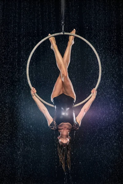 En ung flicka utför de akrobatiska inslagen i aerial hoop. Svart Aqua Studio — Stockfoto