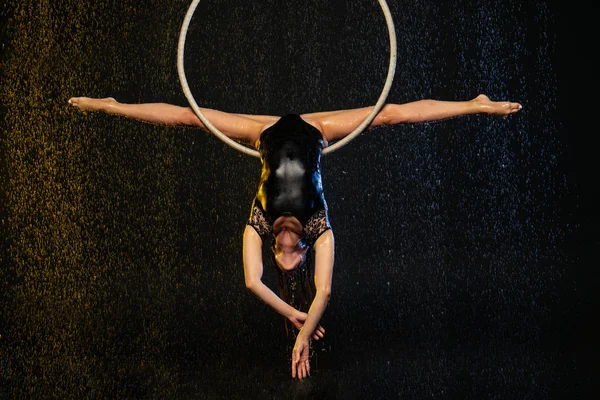 En ung flicka utför de akrobatiska inslagen i aerial hoop. Svart Aqua Studio — Stockfoto