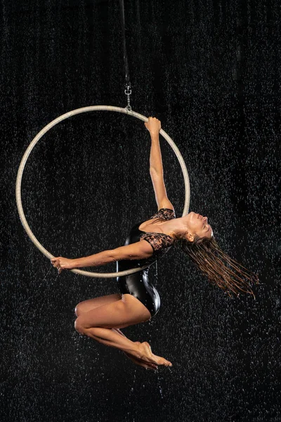 En ung flicka utför de akrobatiska inslagen i antenn ringen. Aqua Studio fotografering föreställningar på en svart bakgrund — Stockfoto