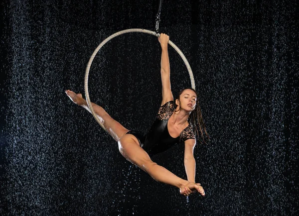 En flexibel flicka utför splittringen i antenn ringen. Aqua Studio fotografering föreställningar på en svart bakgrund — Stockfoto