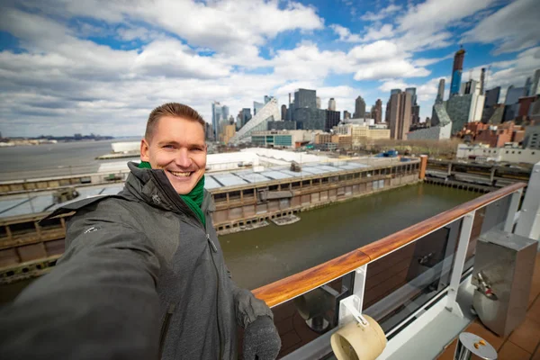 Jovem faz selfie com enorme navio de cruzeiro e Nova York no fundo. Conceito de férias felizes e viagens — Fotografia de Stock