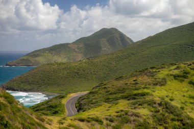 arka planda bulutlar ile dağlar ve mavi deniz arasında muhteşem bir yol