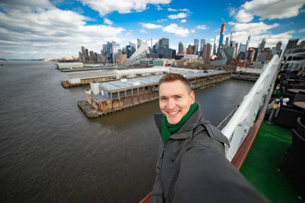 Jovem faz selfie com enorme navio de cruzeiro e Nova York no fundo. Conceito de férias felizes e viagens — Fotografia de Stock