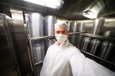 Restoranın mutfak deposunda metal raflarda, tabak yığınlarıyla selfie çeken genç adam.