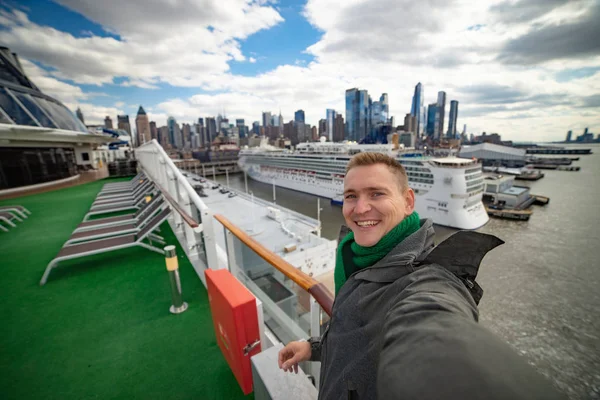 Joven hace selfie con gran crucero y la ciudad de Nueva York en el fondo. Concepto de vacaciones felices y viajes — Foto de Stock