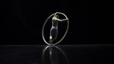 Siyah bir arka plan üzerinde tiyatro bir Cyr Wheel sirk sanatçı