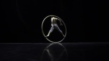 Siyah bir arka plan üzerinde tiyatro bir Cyr Wheel sirk sanatçı