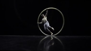 Siyah bir arka plan üzerinde tiyatro bir Cyr Wheel sirk sanatçı