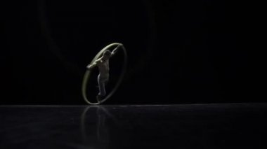 Siyah bir arka plan üzerinde tiyatro bir Cyr Wheel sirk sanatçı