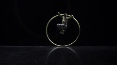 Siyah bir arka plan üzerinde tiyatro bir Cyr Wheel sirk sanatçı