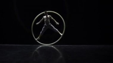 Siyah bir arka plan üzerinde tiyatro bir Cyr Wheel sirk sanatçı