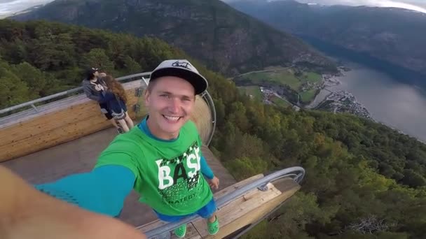 Mirador de Stegastein, Noruega - 22 de julio de 2018: Joven viajero tomando selfie en la parte superior del punto de vista con hermoso fiordo en el fondo en Noruega — Vídeos de Stock