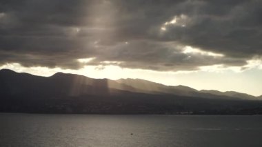 Dağların ve denizin üzerinde güzel ışınları ile dramatik gün batımı
