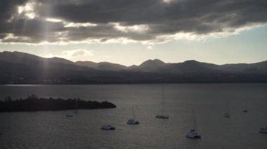 Guadalupe adası yakınlarında arka planda dağ ve bulutlar ile sakin bir suda yelkenli bir sürü