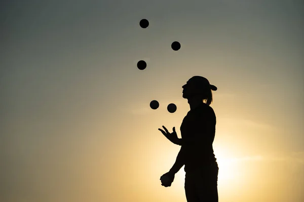 Sziluettje egy férfi Zsonglőrködés a labdákat a Sunset — Stock Fotó