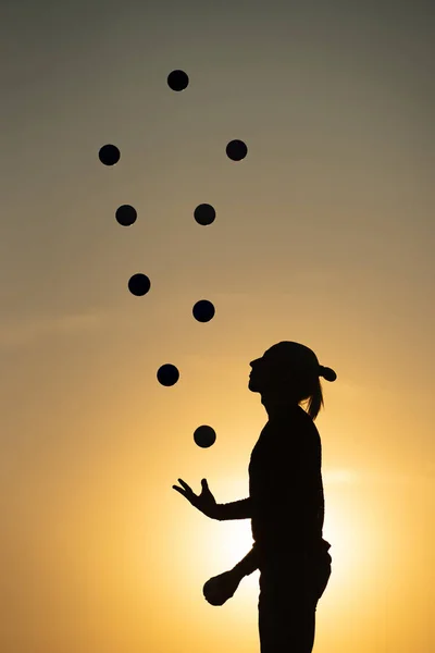 Silhueta de um homem Malabarismo com bolas ao pôr do sol — Fotografia de Stock