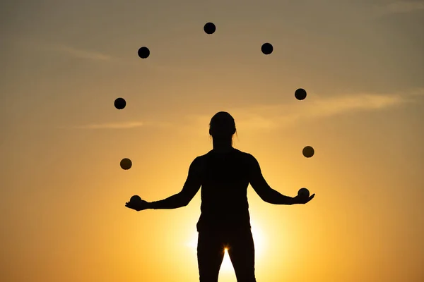 Silhouette d'un homme jonglant avec des boules au coucher du soleil — Photo