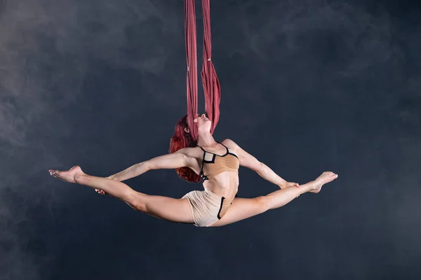 Kvinnlig atletisk, sexig och flexibel antenn cirkusartist med rödhårig dansar i luften på siden — Stockfoto