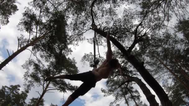 Cirkus artist gör calisthenics i den gröna parken med antenn remmar. — Stockvideo