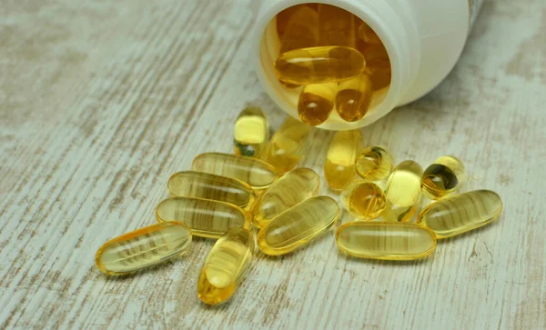 Omega 3 ve D vitamini içeren balık yağı kapsülleri. Plastik bir şişede güneş ışınlı parlak bir doku, sağlıklı beslenme konsepti.