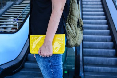 Sırt çantalı ve sarı çantalı genç kadın, havaalanında ya da tren istasyonunda yolcu.