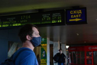Kyiv, Ukrayna - 21 Temmuz 2020: Ukrayna 'nın başkenti Kyiv' de Coronavirus salgını: Yolcular koruyucu maskelerle Merkez Tren İstasyonu boyunca yürüyorlar. Siyah maskeli adam..