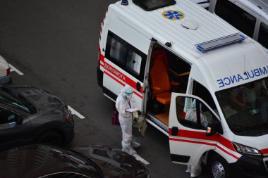 Kyiv, Ukrayna - 13 Ağustos 2020: Koruma kıyafetleri giyen ambulans Kyiv 'deki yüksek binalardan birinin bahçesine çağrıldı.