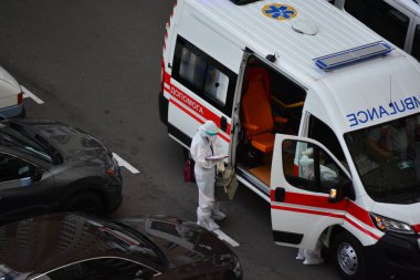 Kyiv, Ukrayna - 13 Ağustos 2020: Koruma kıyafetleri giyen ambulans Kyiv 'deki yüksek binalardan birinin bahçesine çağrıldı.