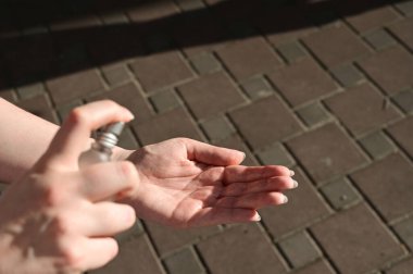 Dışarıda duran genç bir kadın salgın sırasında ellerini hijyen kurallarına göre dezenfekte eder. Pankart karantina, koronavirüs önleyici ve el yıkama konsepti