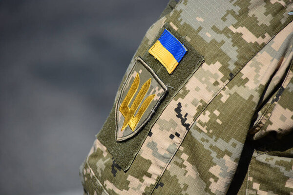 Украинский солдат в военной форме с флагом и шевроном с изображением трезубца - украинская эмблема и национальный символ