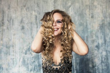 Genç kadın gülüyor. Uzun kıvırcık saçlı güzel kadın modeli