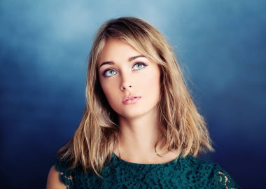 Güzel genç kadın üzerinde mavi arka plan ararken