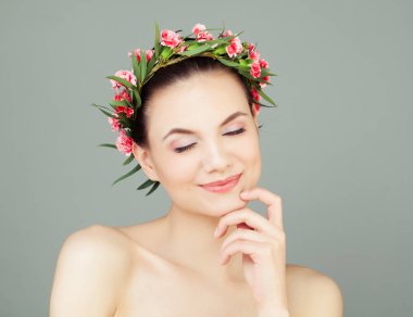 Sağlıklı cilt ve sevimli bir gülümseme düşünce ile kadın. Çiçek ve yeşil yaprakları ile güzel kız