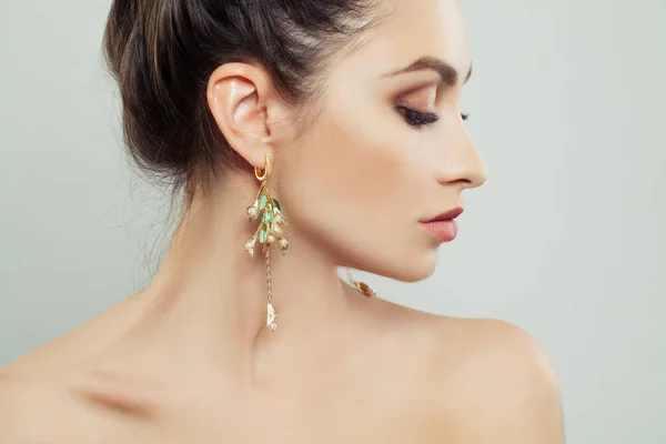 戴着白色珍珠和绿色宝石的金色耳环的漂亮女人 — 图库照片