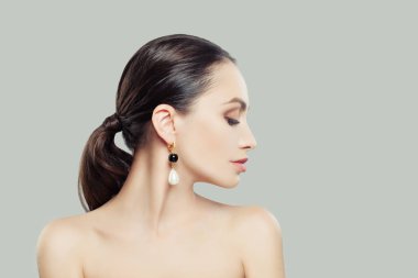 Doğal makyaj ve siyah ve kopya alanı zemin üzerine beyaz inci küpe olan genç kadın. Kadın profili