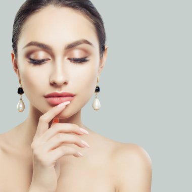 Doğal makyaj ve inci küpeli güzel kadın