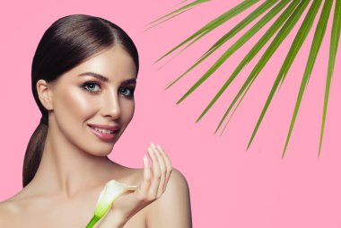 Sağlıklı cilt ve pembe bir arka plan üzerinde beyaz çiçekler güzel genç kadın. Yüz tedavi, kozmetik ve spa tedavisi